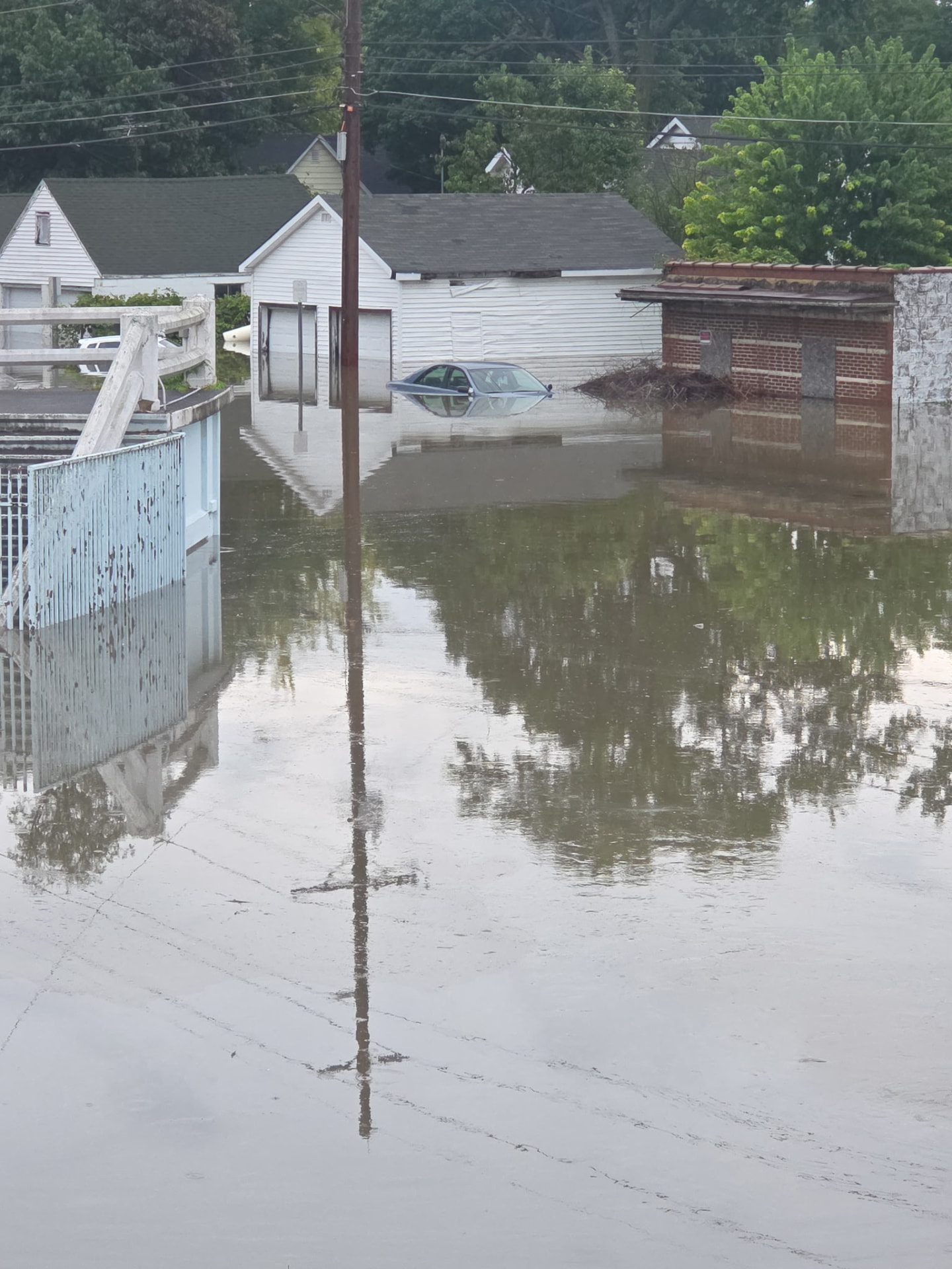 Car submerged in flood water beside flooded garages